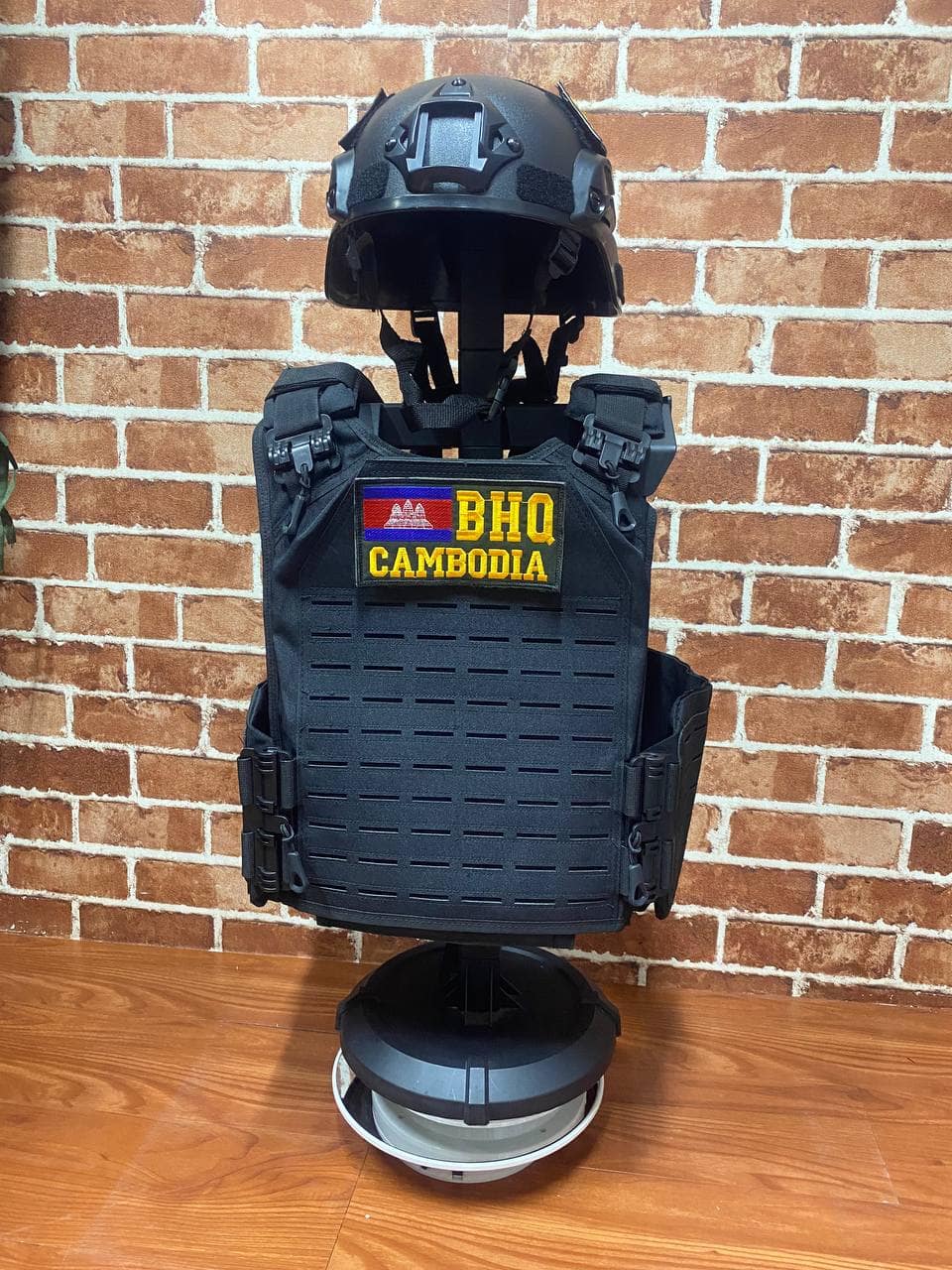 Black tactical vest with Cambodia patch and helmet on display.
