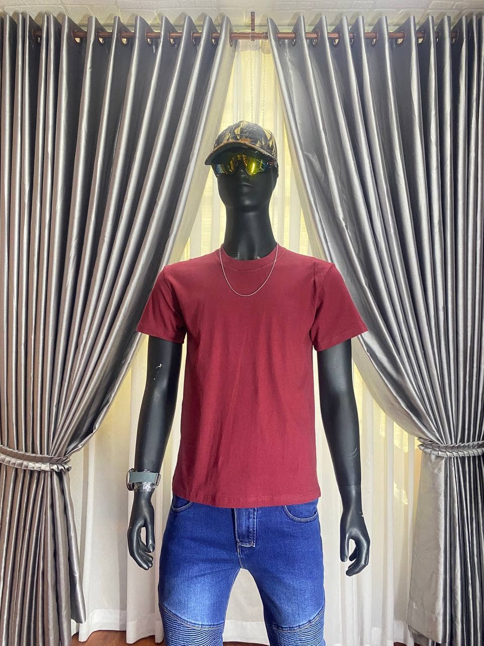 Red t-shirt with cap and sunglasses on mannequin in store display.