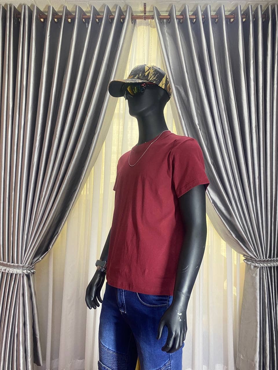 Red casual T-shirt with camouflage cap and sunglasses on mannequin.