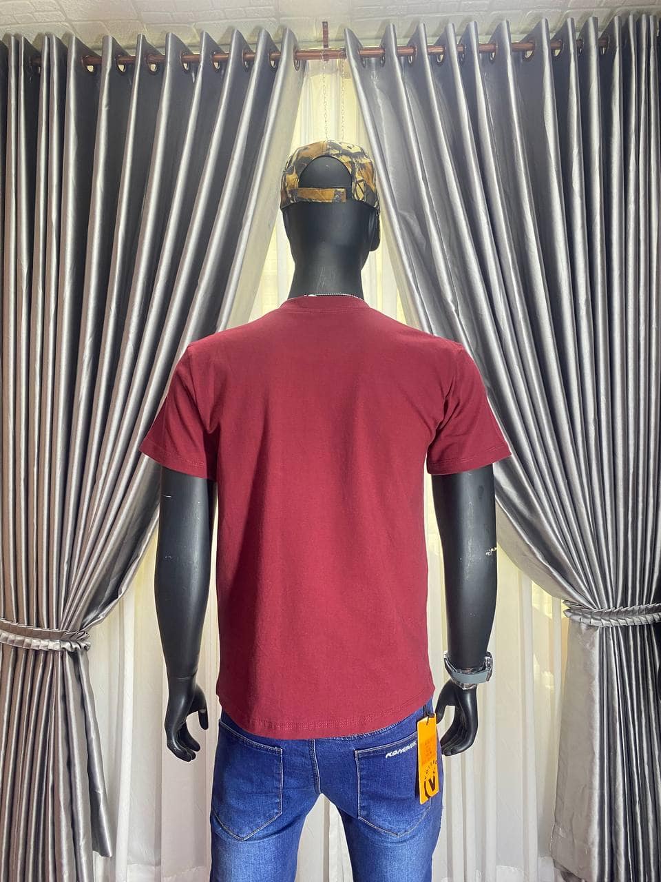 Red tactical T-shirt on black mannequin with camouflage cap in store.