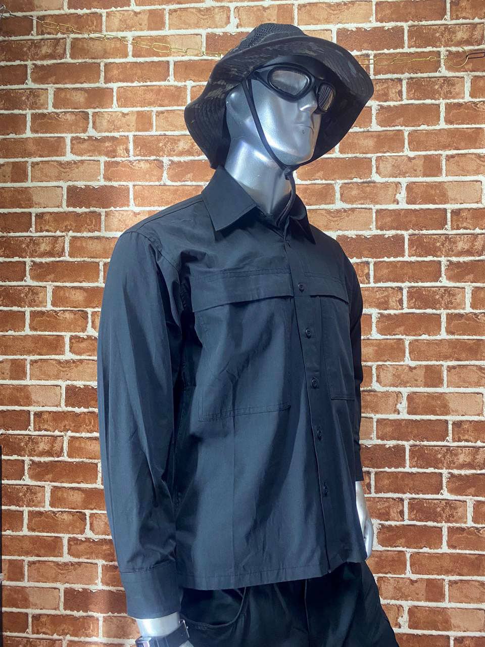 Black tactical shirt with long sleeves and front pockets, displayed on mannequin.
