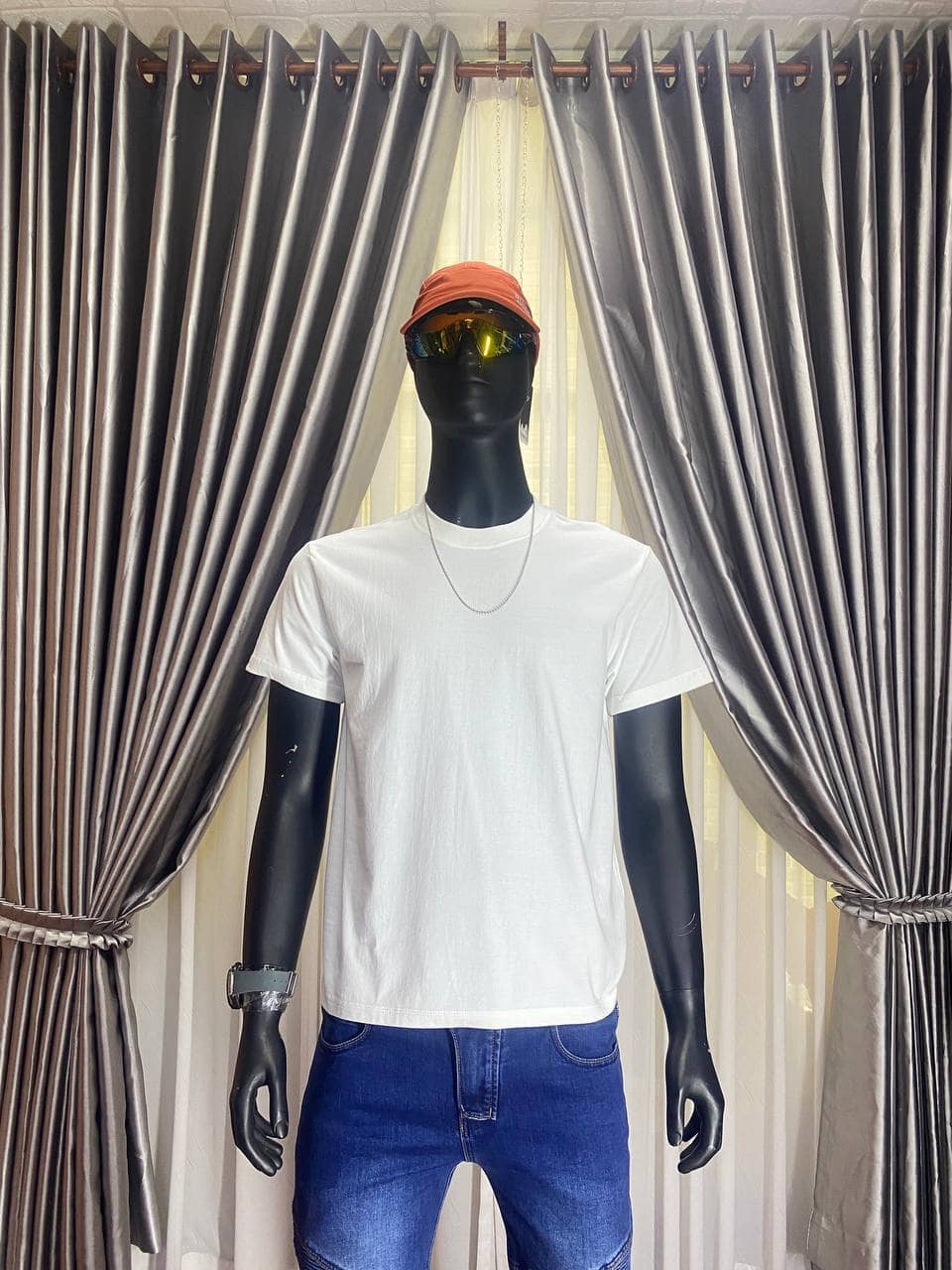 White T-shirt with orange cap and sunglasses on mannequin display.
